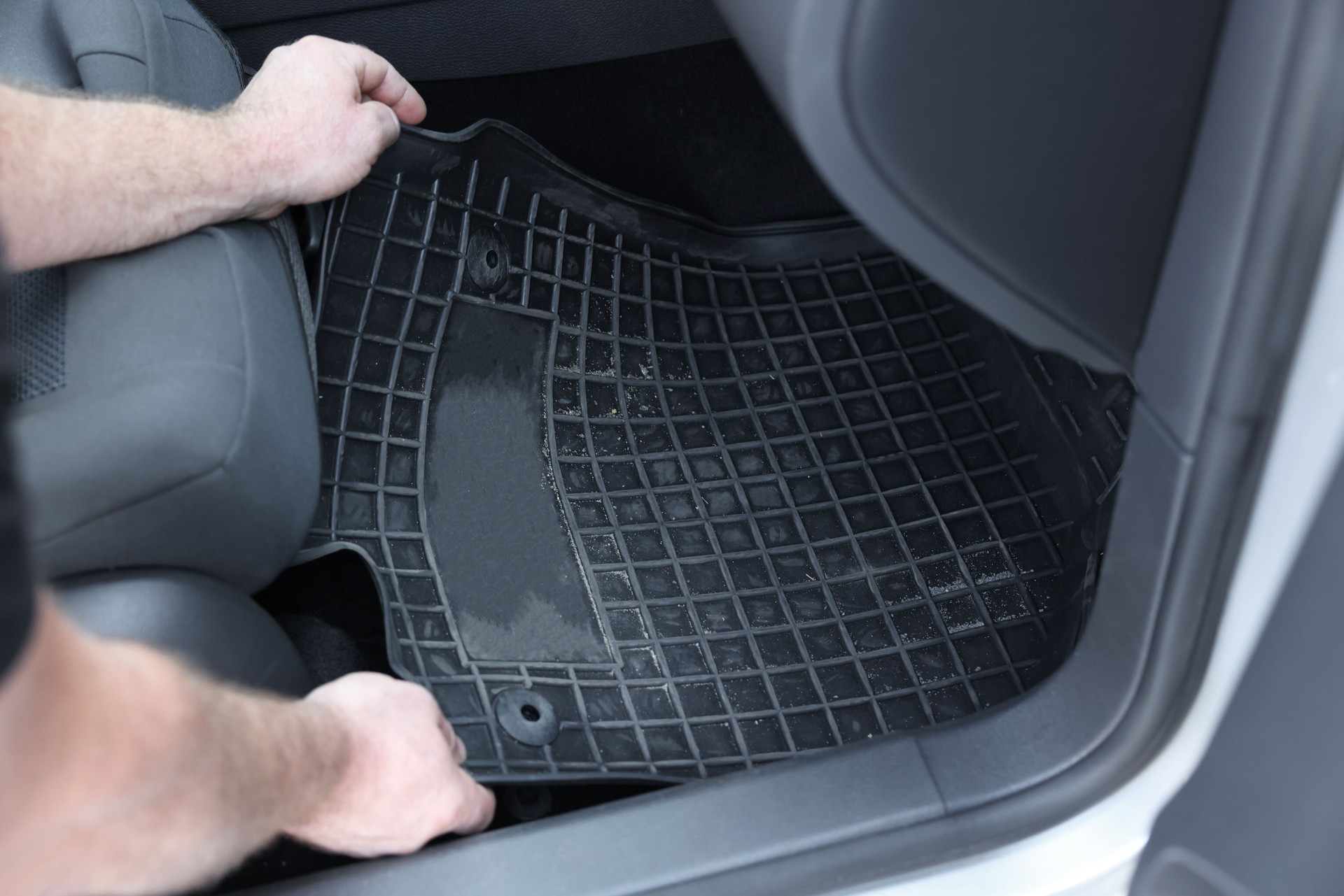 Man taking black rubber car mat from auto, closeup