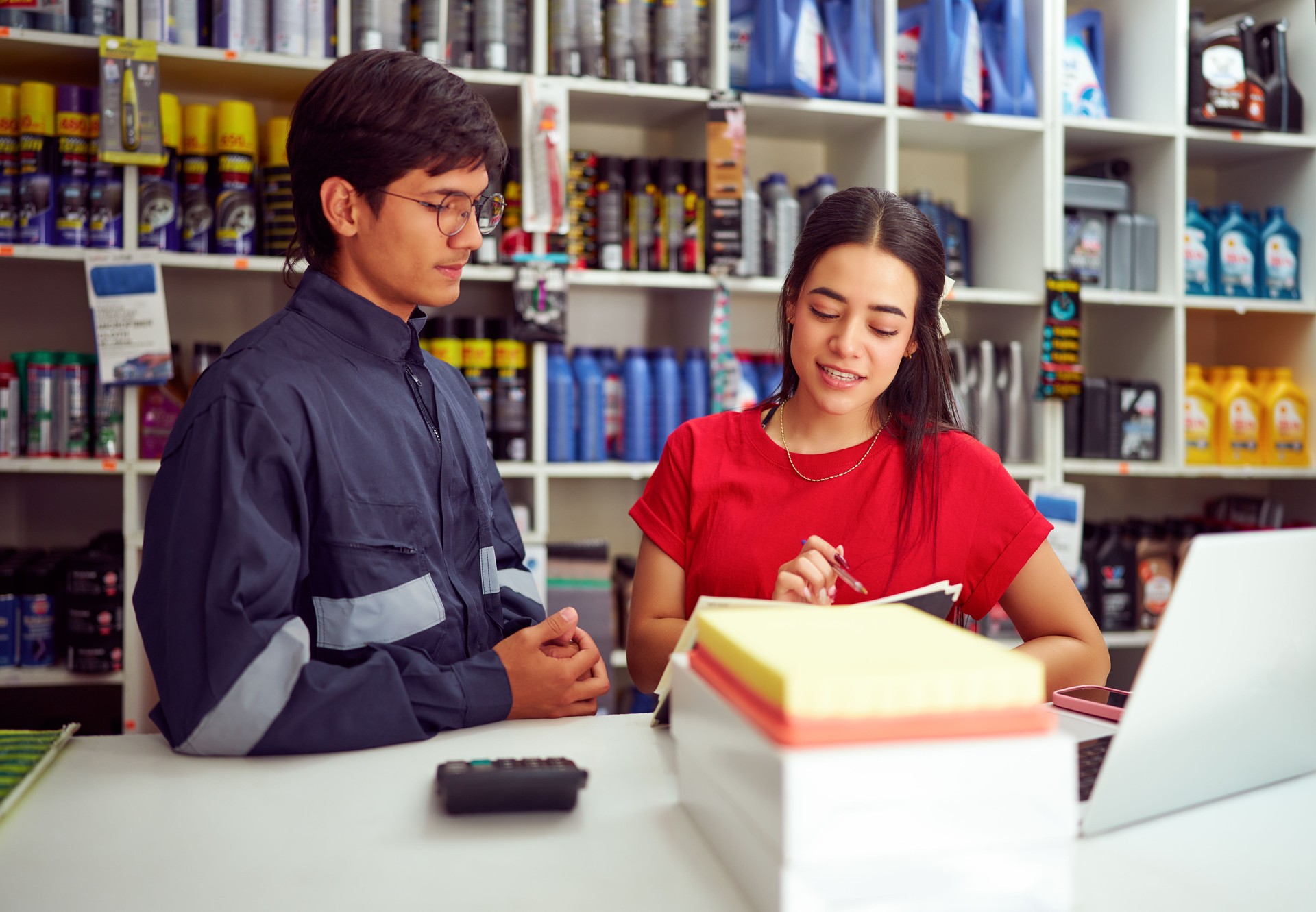 Mechanic discussing auto parts order with store clerk in auto supply shop